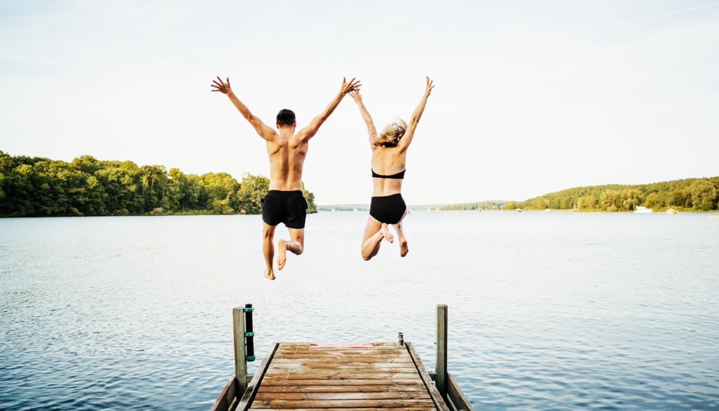 Couple sautant d'un ponton pour nager